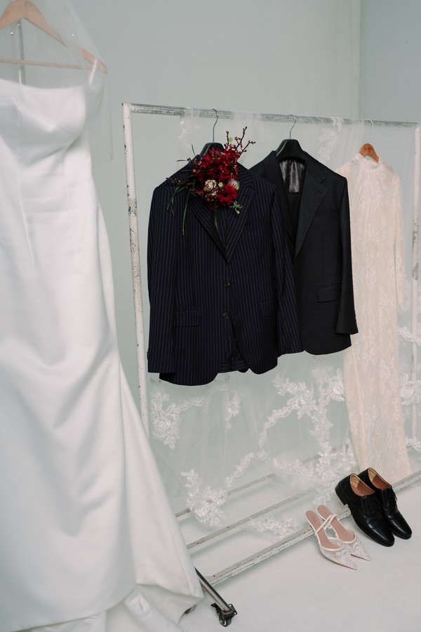 Bộ suit xanh Nobility treo cạnh váy cưới lụa trắng