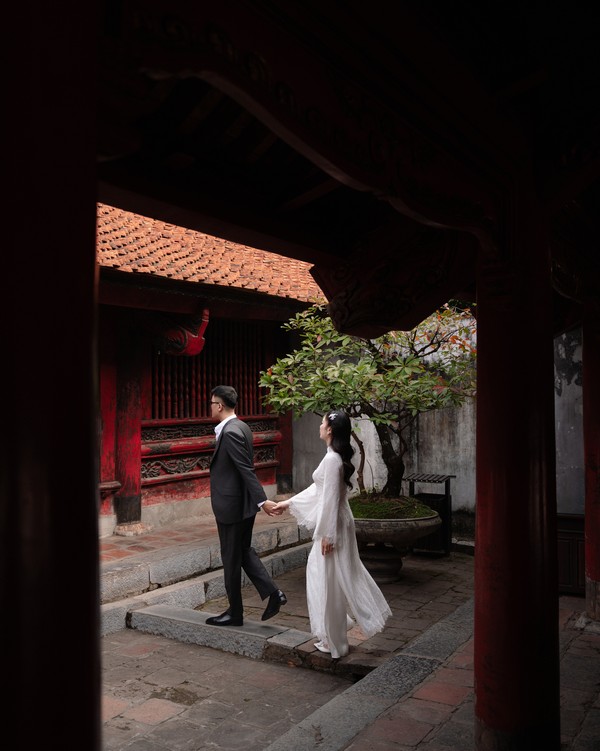 Cặp đôi bước đi qua cổng tò vò mái ngói rêu