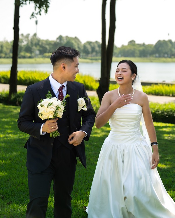 Cặp đôi sánh bước bên hàng cây xanh và mặt hồ phẳng lặng