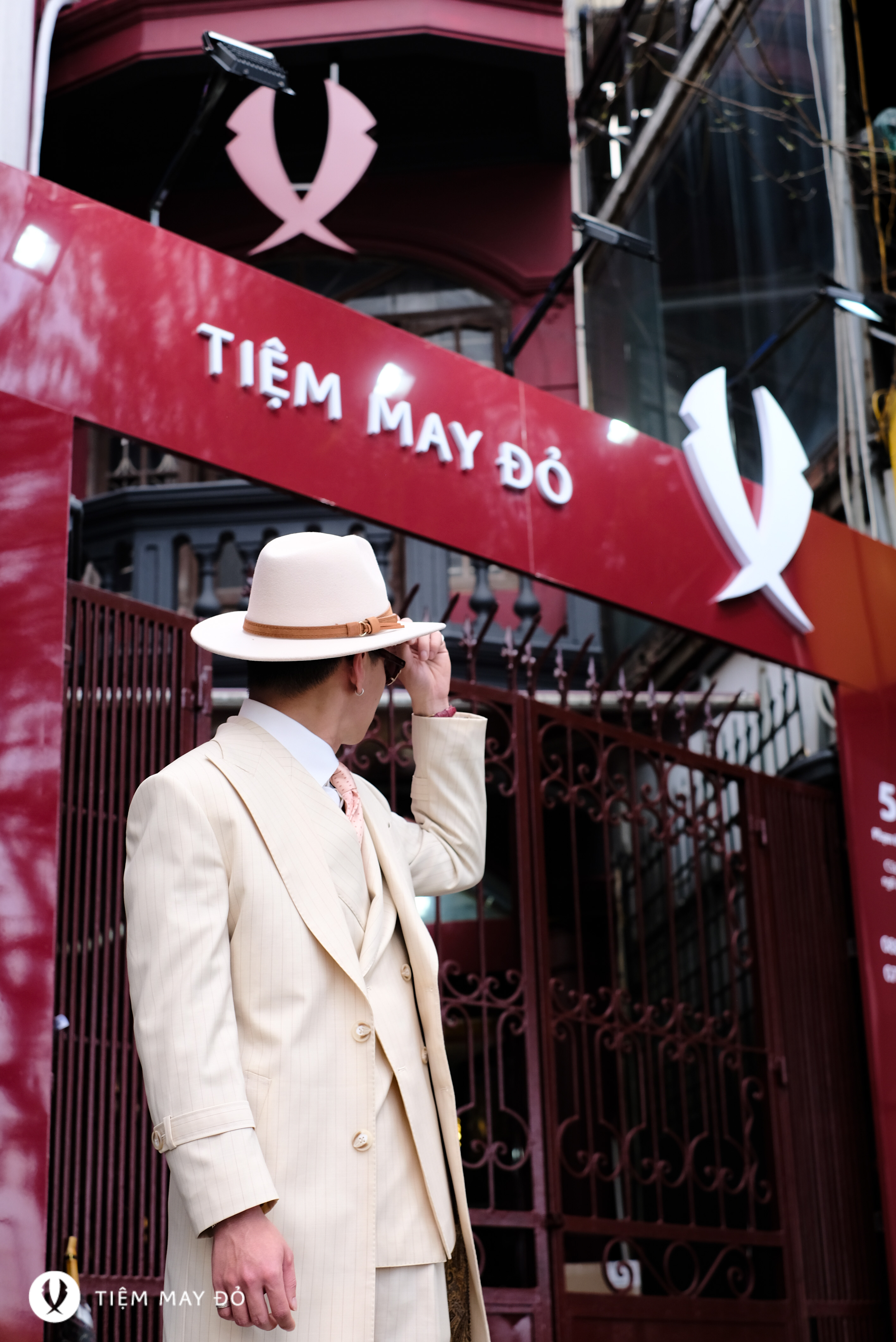 Quý ông đội mũ fedora trước cửa hiệu Tiệm May Đỏ
